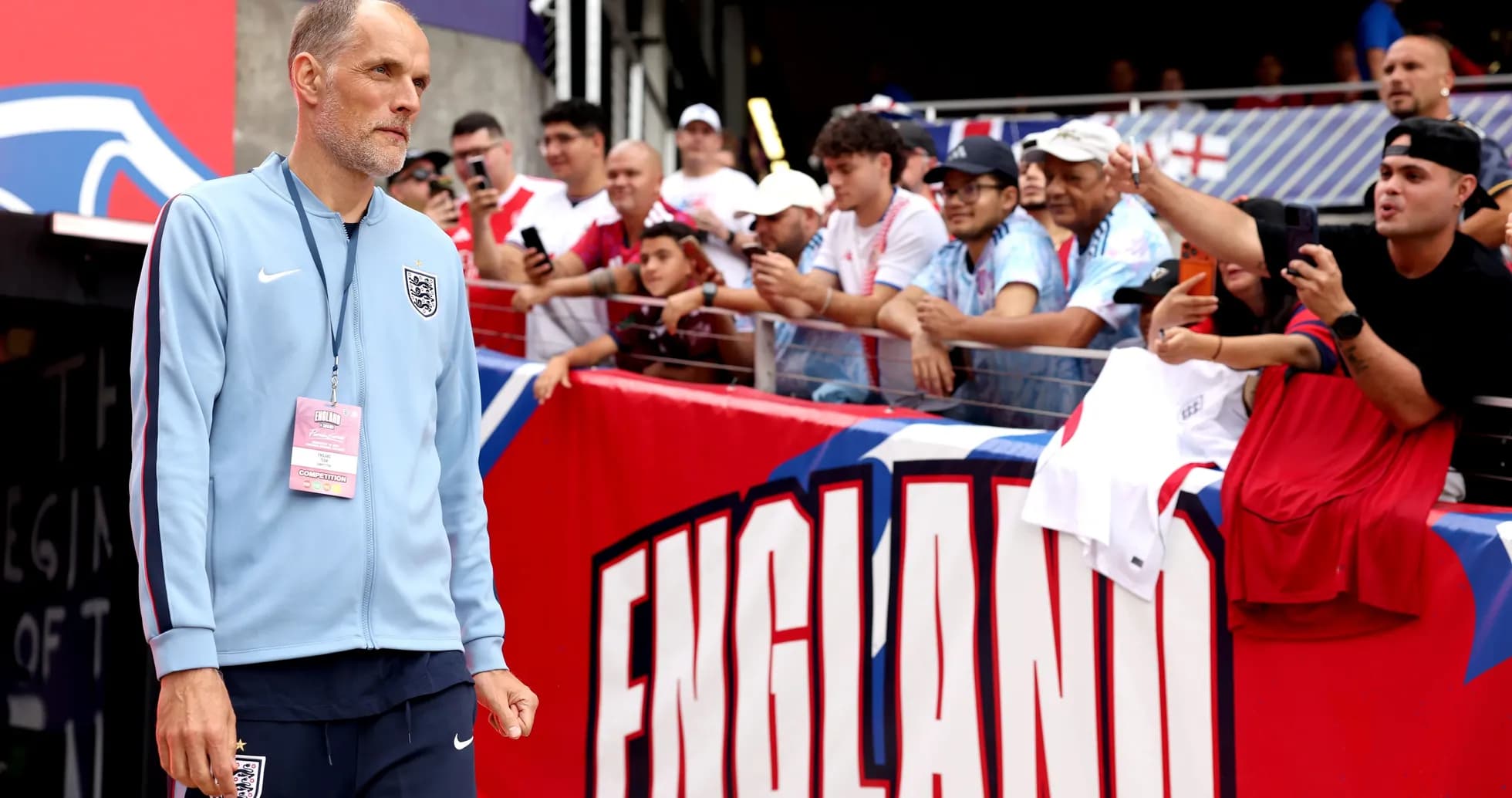 Entrenador caminando hacia la cancha con aficionados detrás