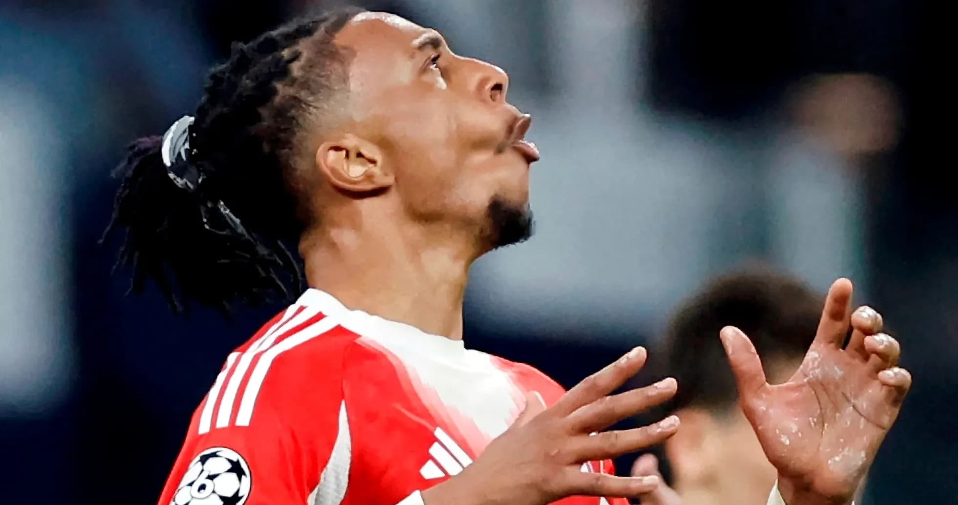 Jugador de fútbol con camiseta roja mirando hacia arriba