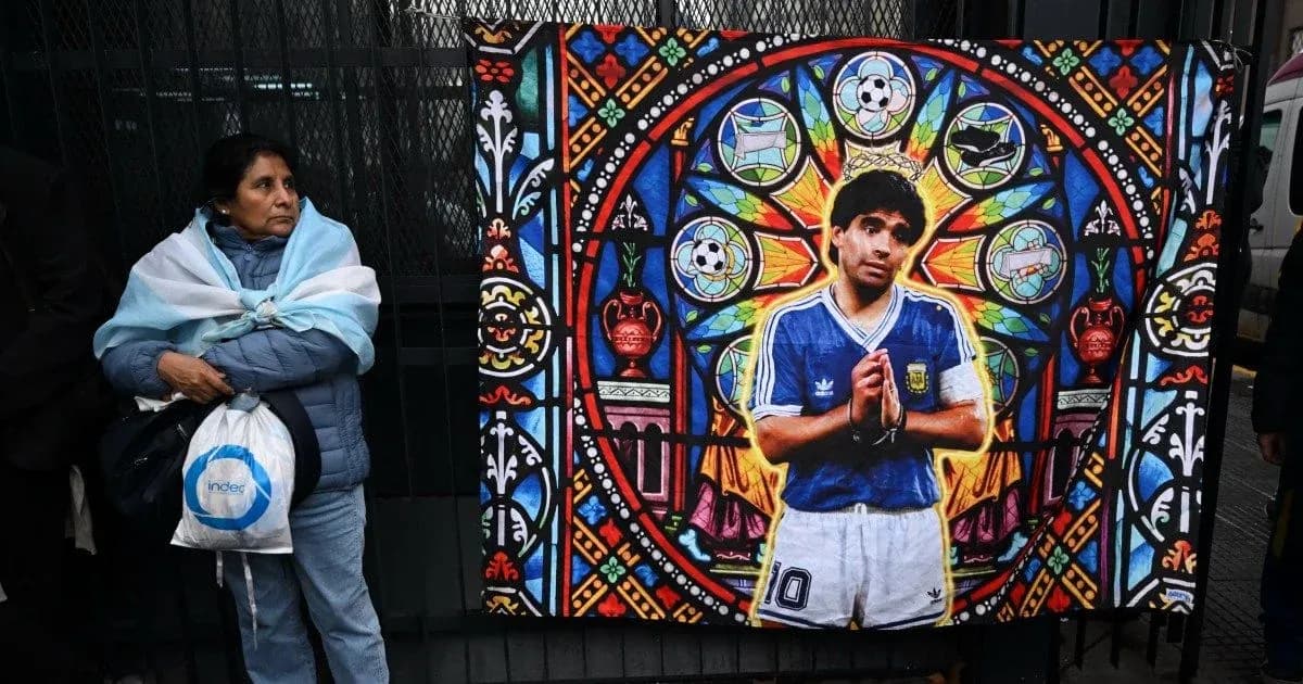 Mujer con bandera argentina junto a mural de Maradona