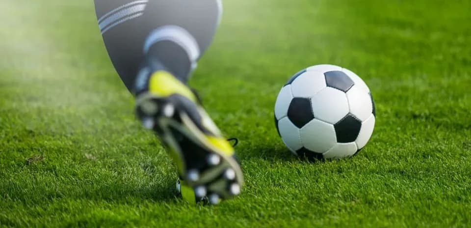 Jugador golpeando un balón de fútbol en césped