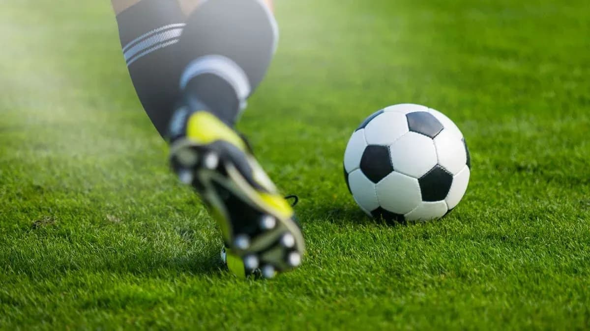 Jugador golpeando un balón de fútbol en césped