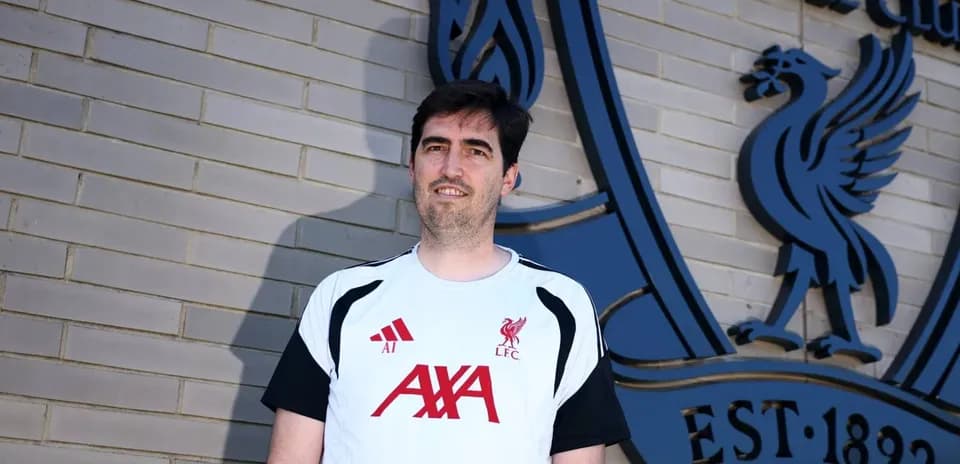 Entrenador posando frente al escudo del Liverpool