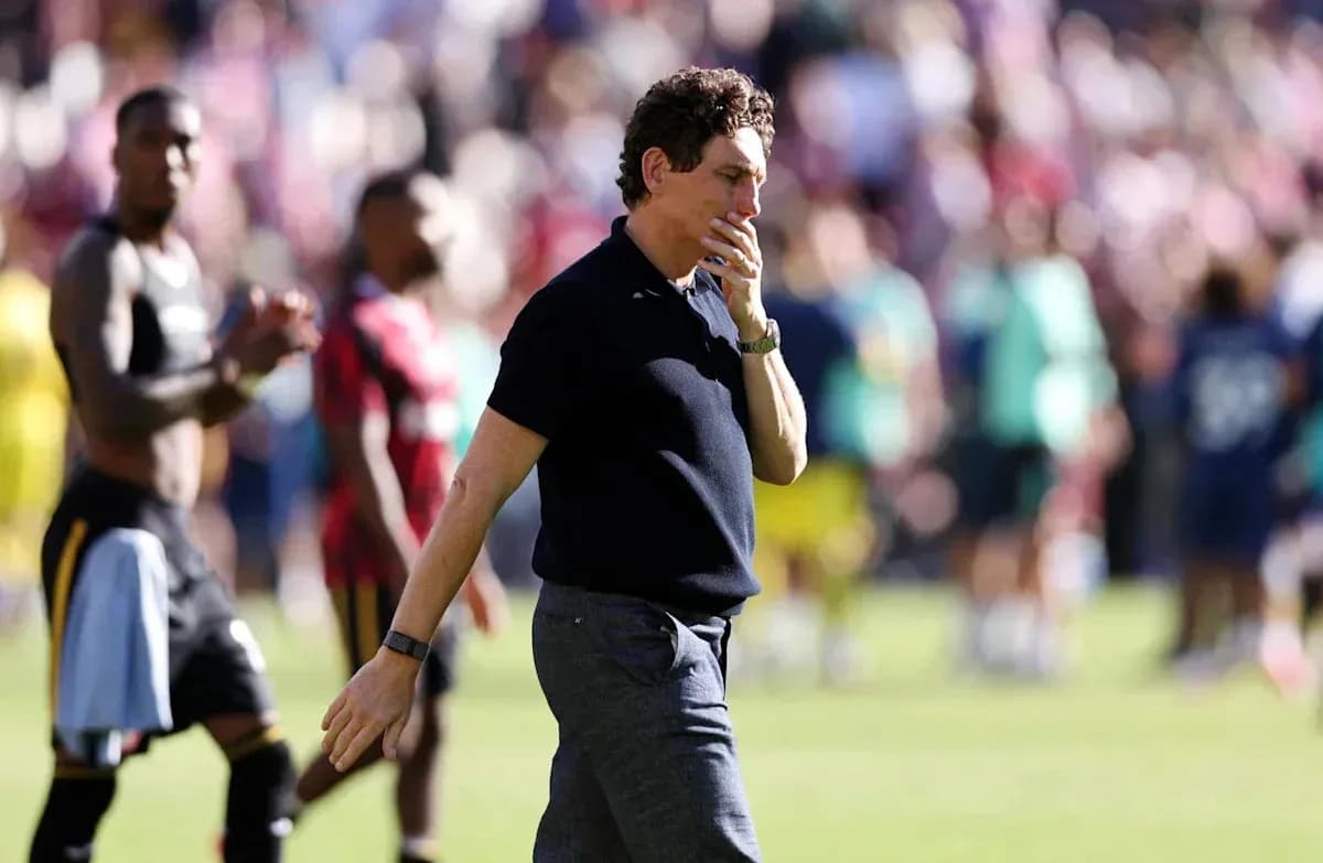 Entrenador caminando tras el partido con jugadores de fondo