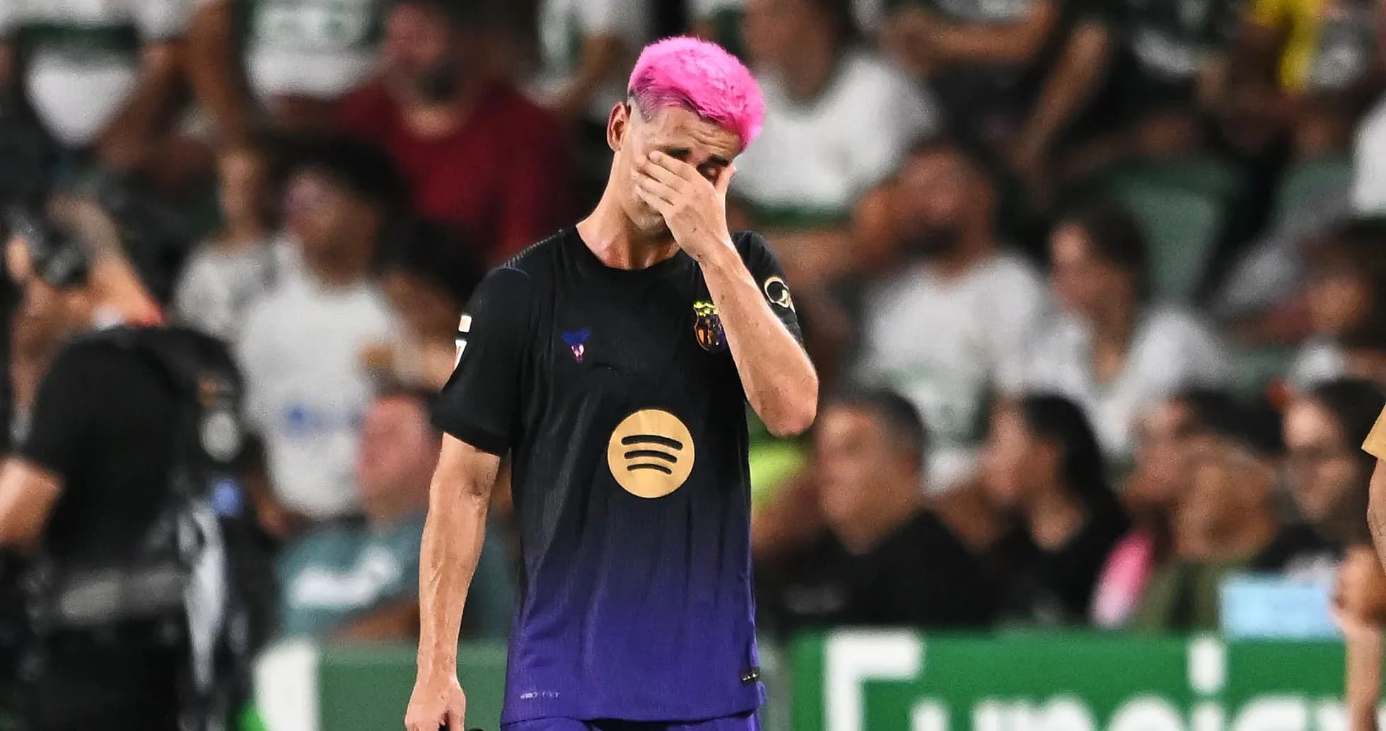 Jugador con cabello rosa se lamenta en el campo