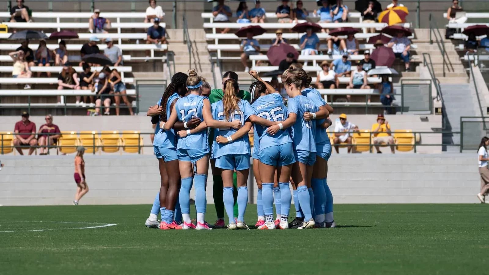 Equipo femenino de fútbol formando un círculo en el campo