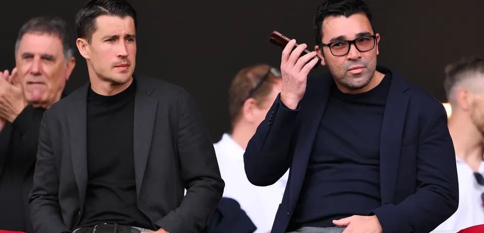 Dos hombres observando un evento deportivo desde las gradas