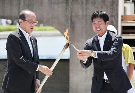 Dos hombres encendiendo una antorcha durante ceremonia