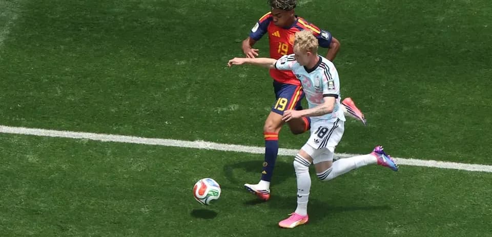 Jugador español defendiendo contra jugador alemán en el campo