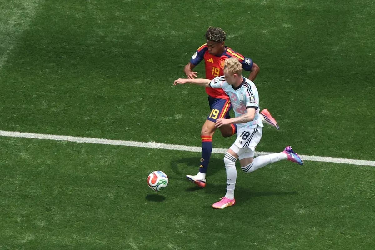 Jugador español defendiendo contra jugador alemán en el campo
