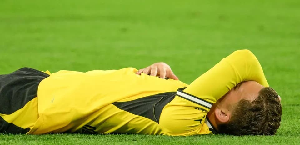 Jugador tendido en el campo con camiseta amarilla