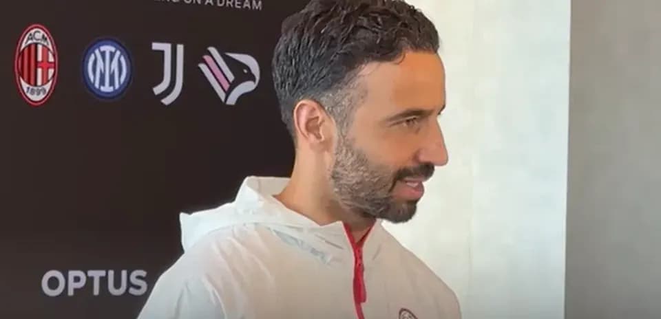 Persona hablando en conferencia de prensa con logos de equipos