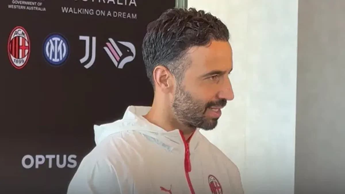 Persona hablando en conferencia de prensa con logos de equipos
