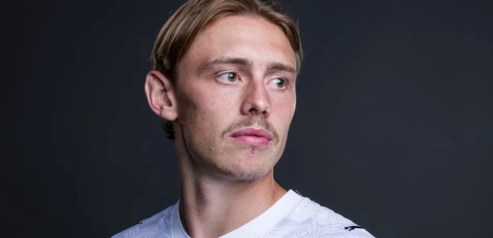Jugador de fútbol posando con camiseta blanca