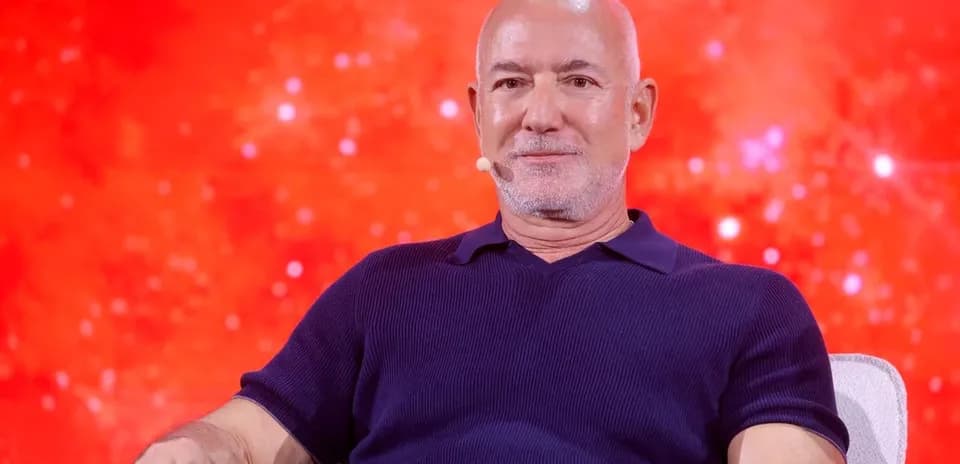 Hombre hablando en un evento con fondo rojo