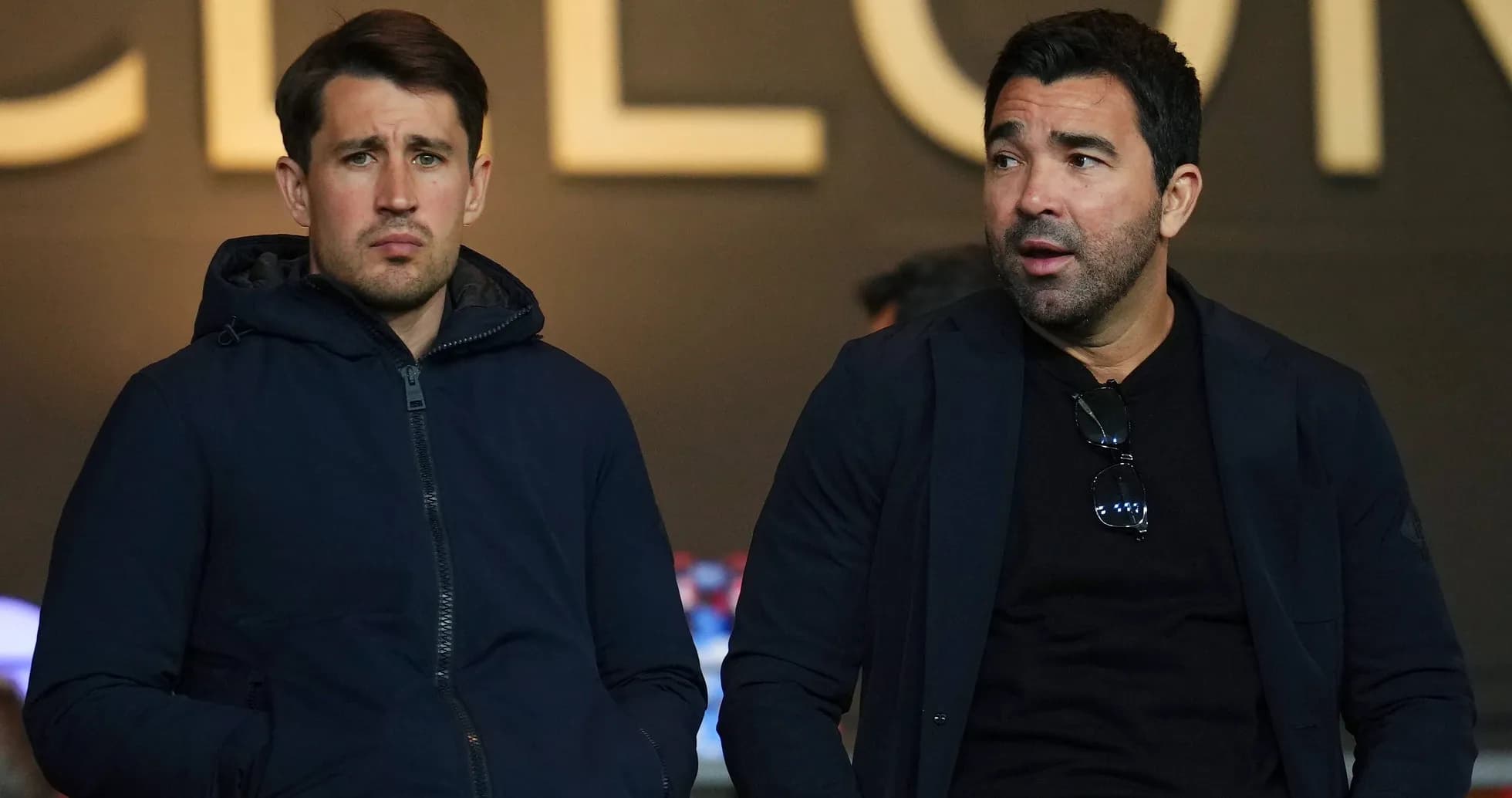 Dos hombres sentados en un evento deportivo