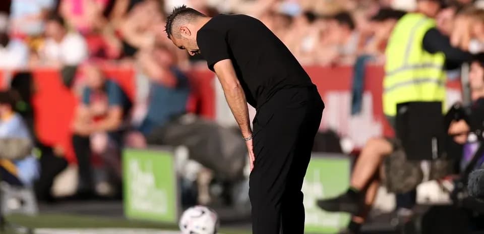 Entrenador mirando hacia abajo junto al balón