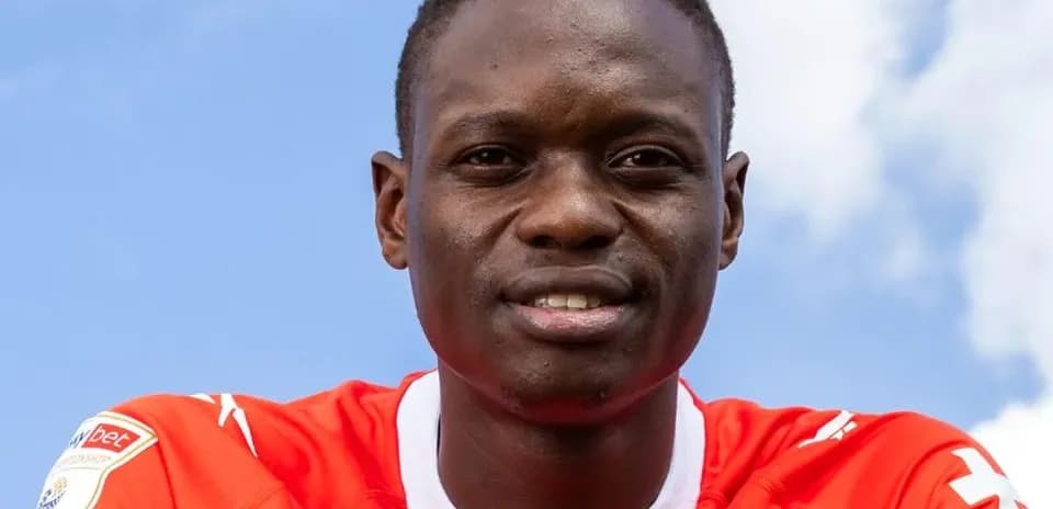 Jugador sonriente con camiseta roja frente al cielo
