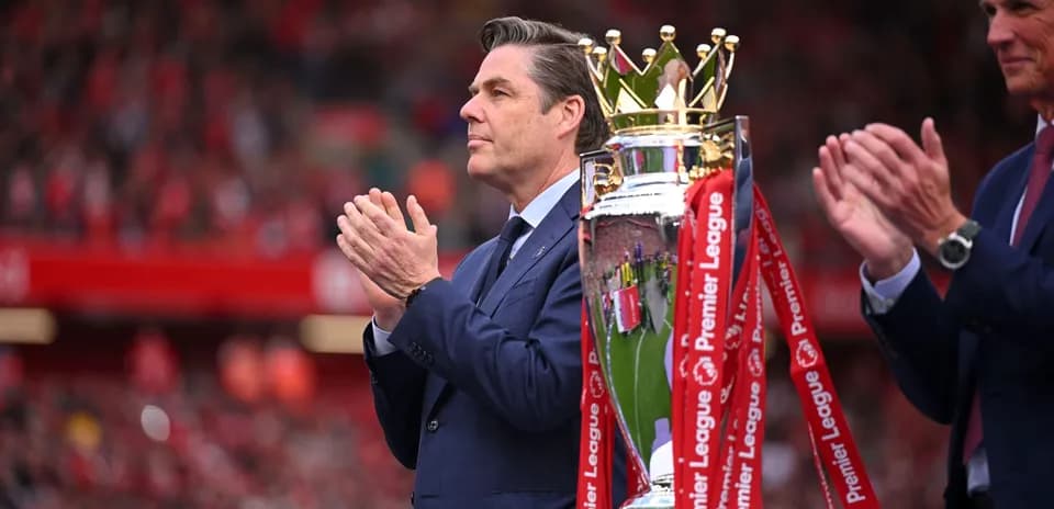 Hombre aplaudiendo junto al trofeo de la Premier League