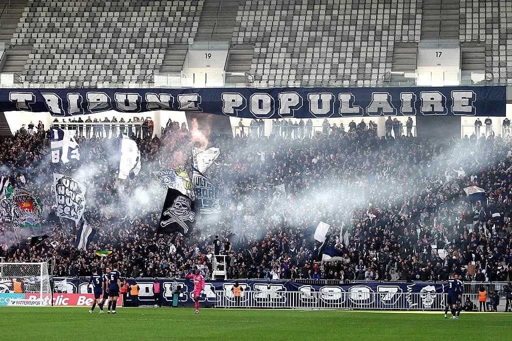 Aficionados animando en el estadio con humo y banderas