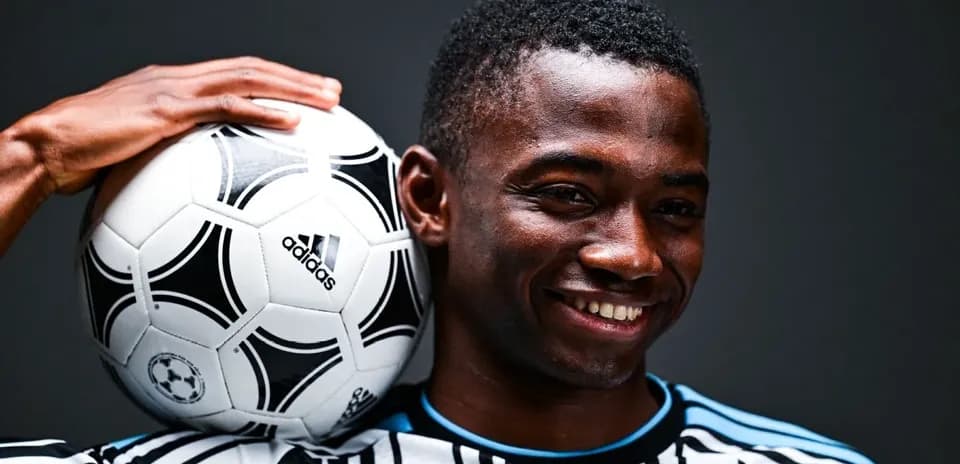 Jugador sosteniendo un balón de fútbol en hombro