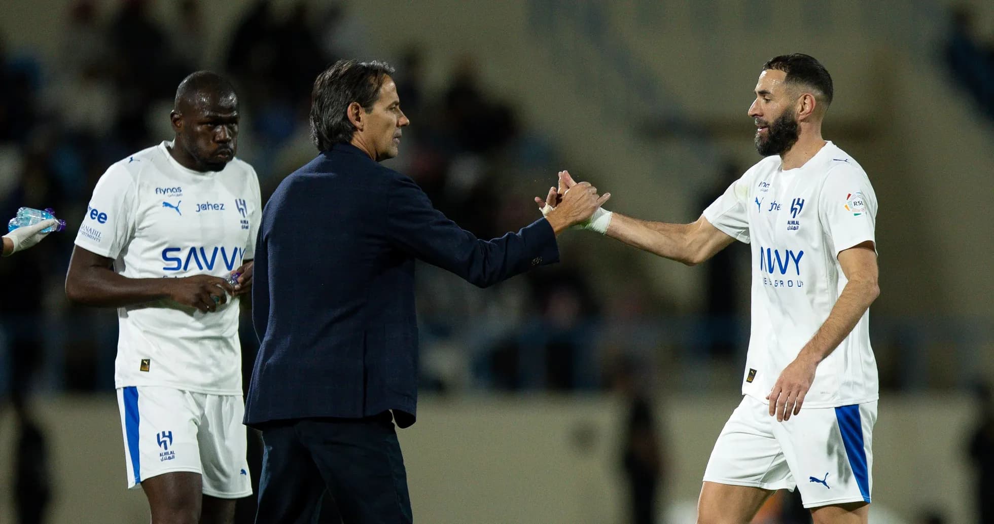 Entrenador saludando a jugador tras cambio en partido