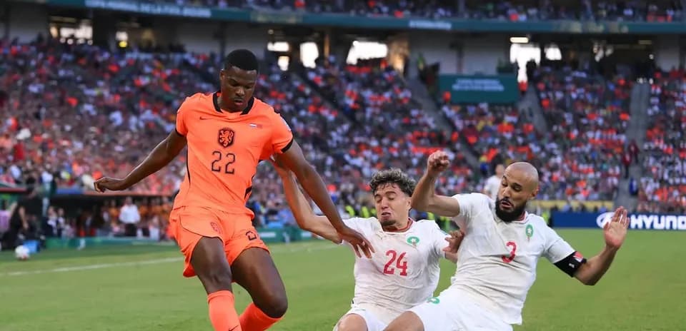 Jugador de Países Bajos driblando entre dos rivales
