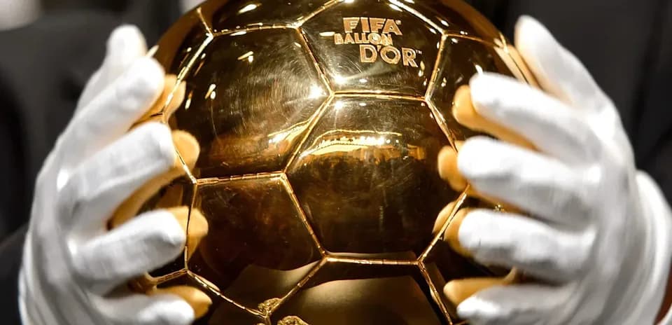 Trofeo Balón de Oro sostenido por manos enguantadas