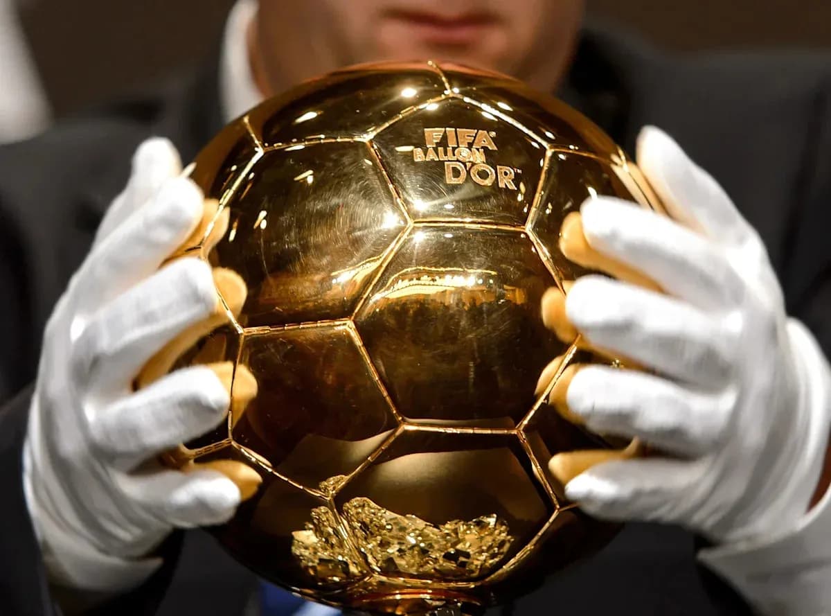 Trofeo Balón de Oro sostenido por manos enguantadas