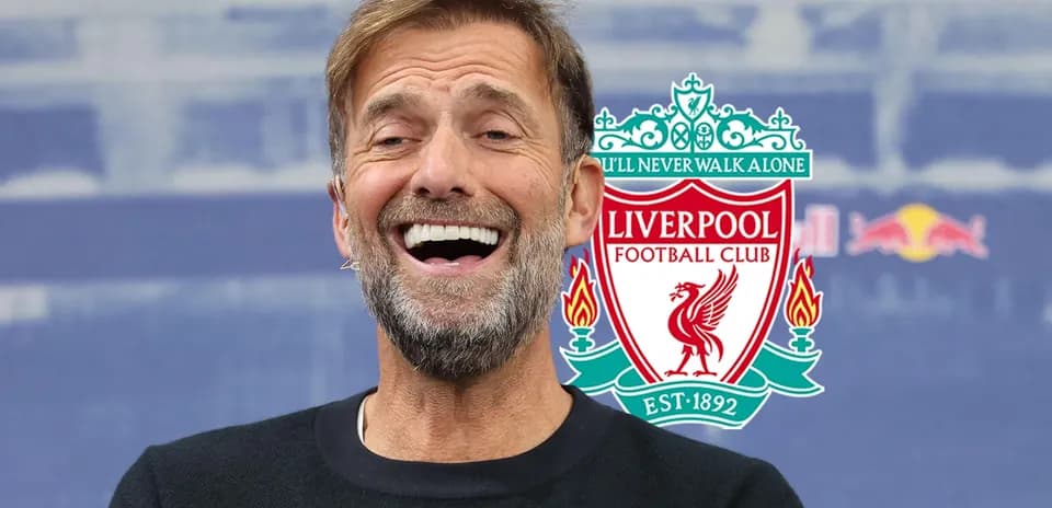 Entrenador sonriendo con logo de Liverpool detrás