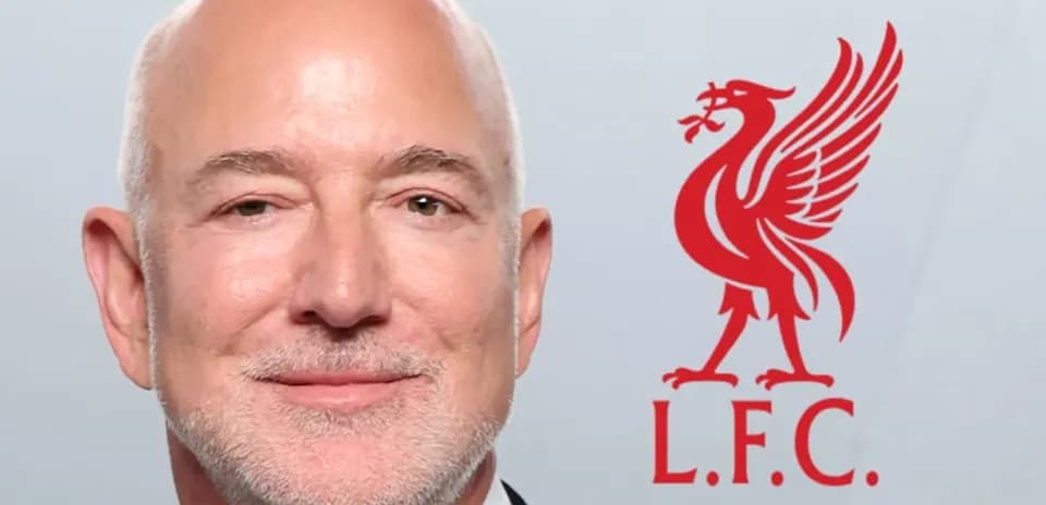 Hombre sonriendo con el logo de Liverpool detrás