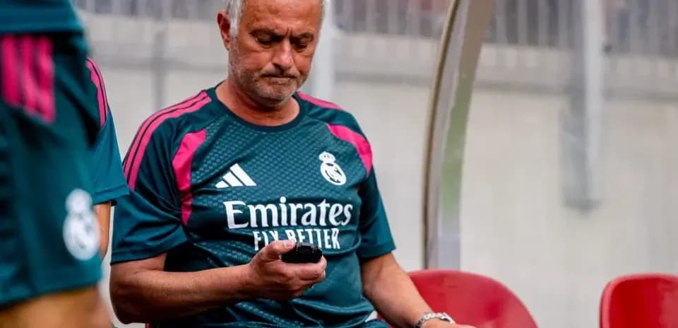 Entrenador sentado en el banquillo revisando su teléfono