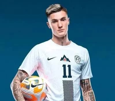 Jugador sosteniendo un balón en uniforme blanco