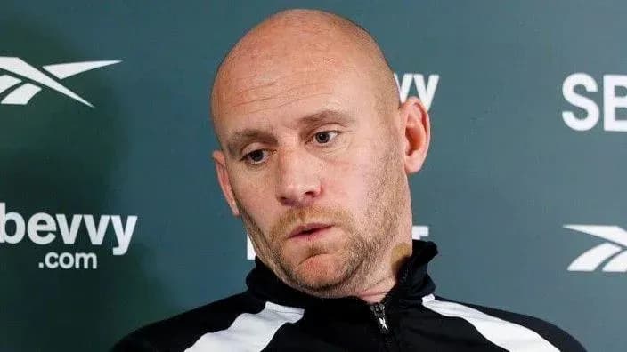 Entrenador en conferencia de prensa, mirada pensativa
