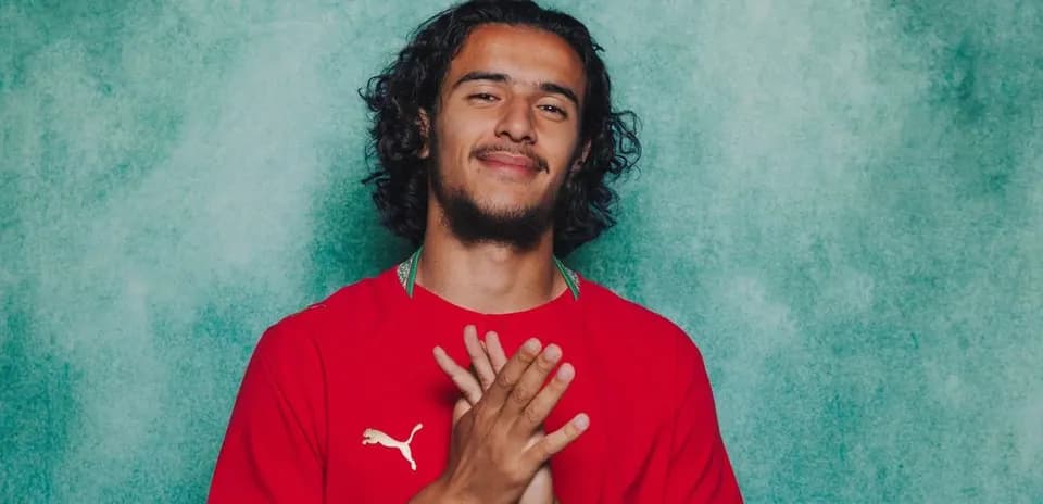 Jugador posando con camiseta roja en fondo verde