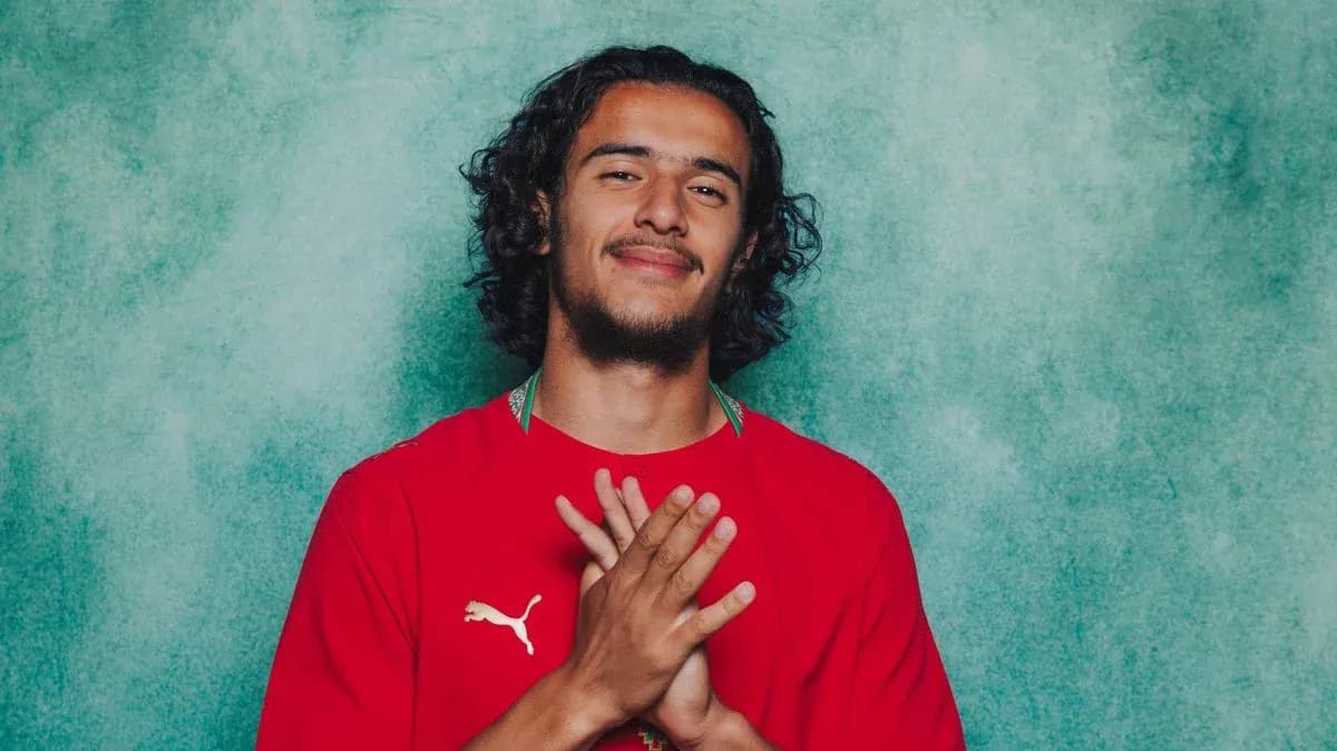 Jugador posando con camiseta roja en fondo verde