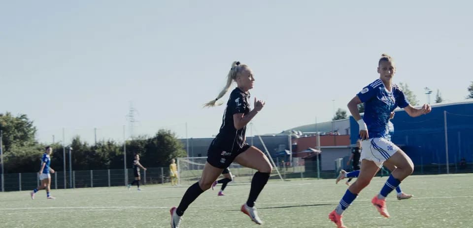 Jugadoras corriendo en partido de fútbol femenino