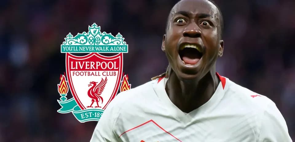 Jugador celebrando con el escudo de Liverpool detrás