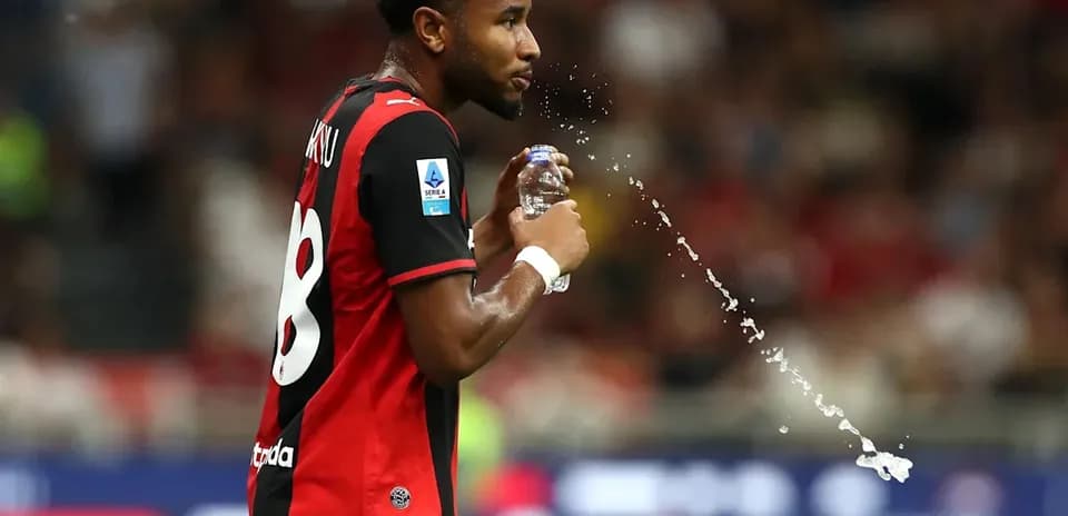 Jugador con camiseta negra y roja bebiendo agua
