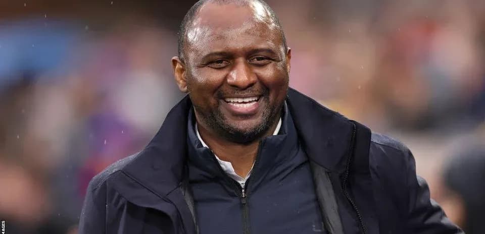 Entrenador sonriendo durante un partido de fútbol