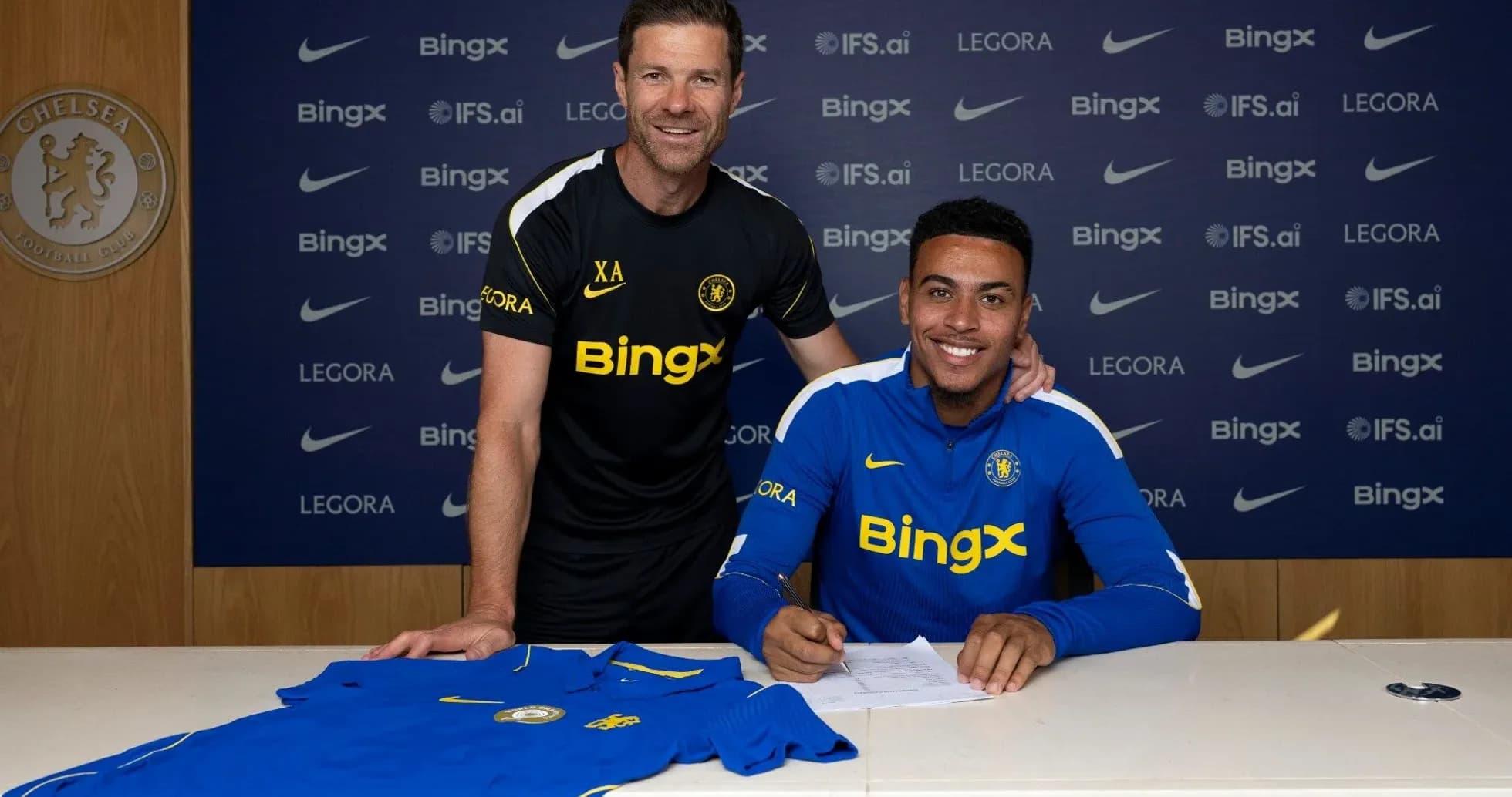 Jugador firmando contrato con entrenador en mesa Jugador firmando contrato con entrenador en mesa