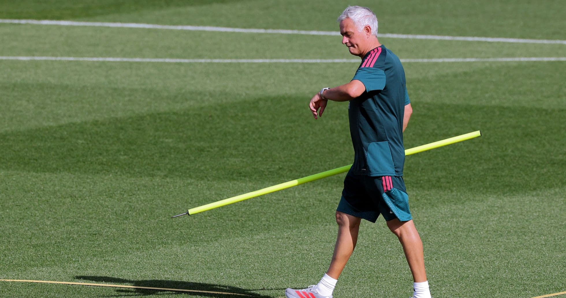 Entrenador caminando con varilla en el campo de entrenamiento Entrenador caminando con varilla en el campo de entrenamiento