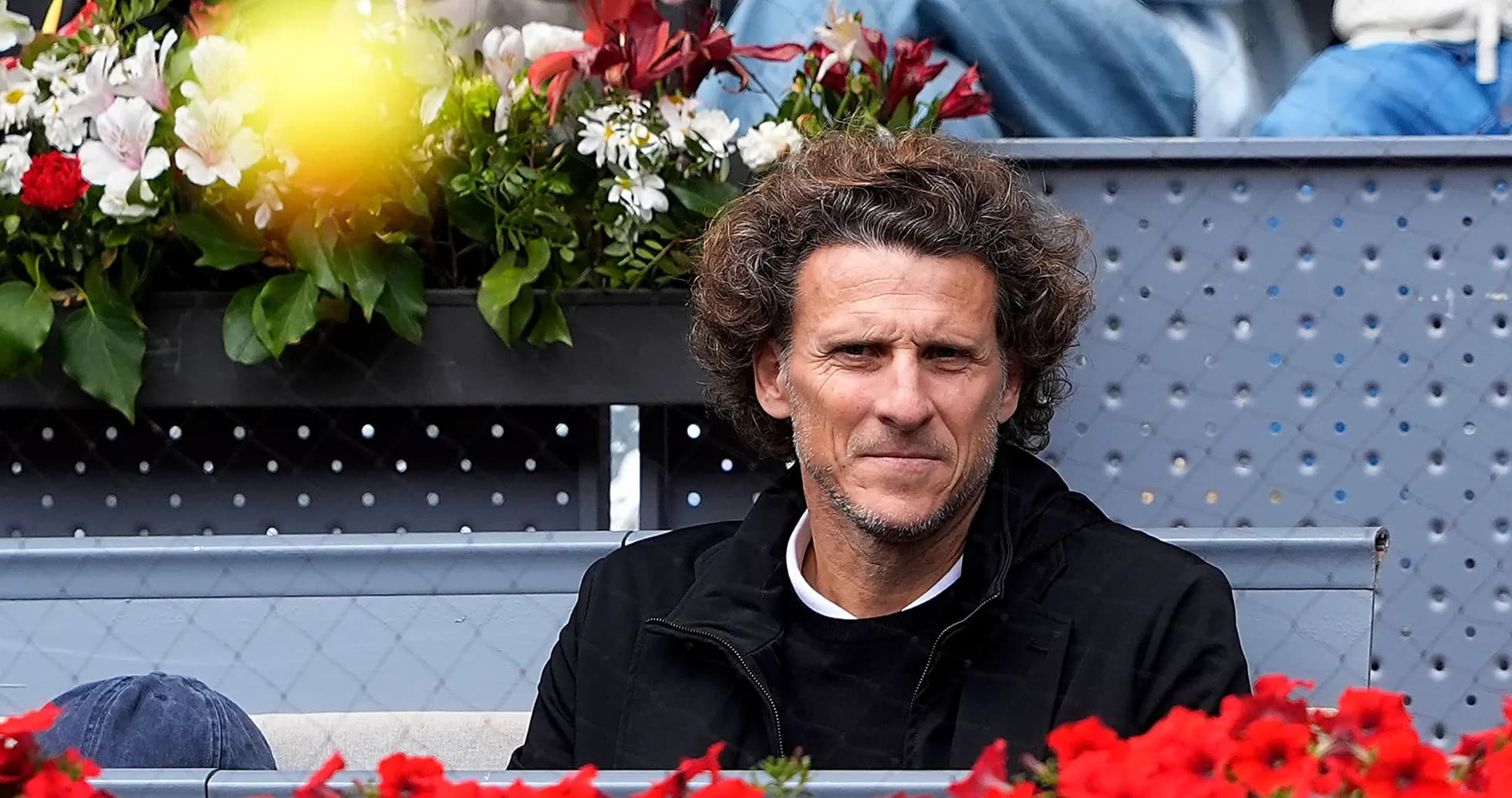 Hombre sentado en gradas con flores alrededor Hombre sentado en gradas con flores alrededor
