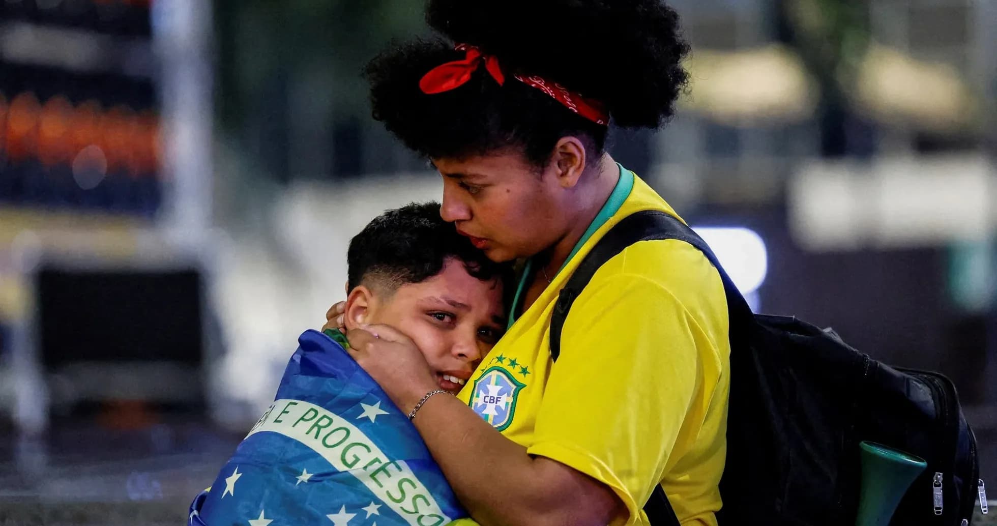 Mujer abrazando a niño envuelto en bandera brasileña Mujer abrazando a niño envuelto en bandera brasileña