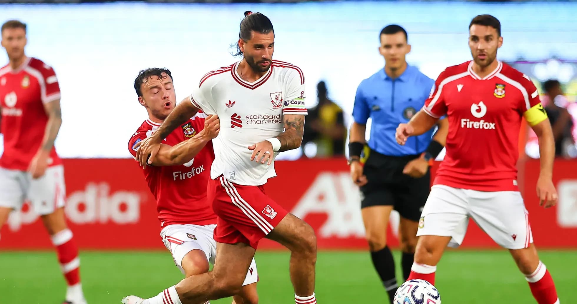 Jugador de Liverpool driblando mientras es marcado por rival Jugador de Liverpool driblando mientras es marcado por rival