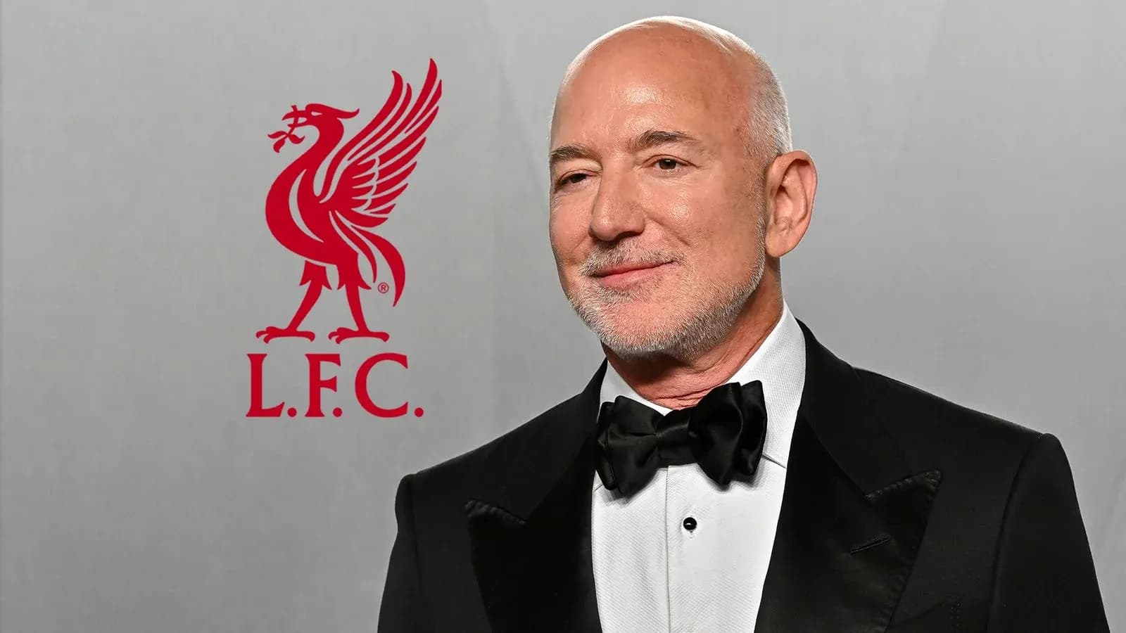 Hombre con traje en evento junto a logo de Liverpool Hombre con traje en evento junto a logo de Liverpool