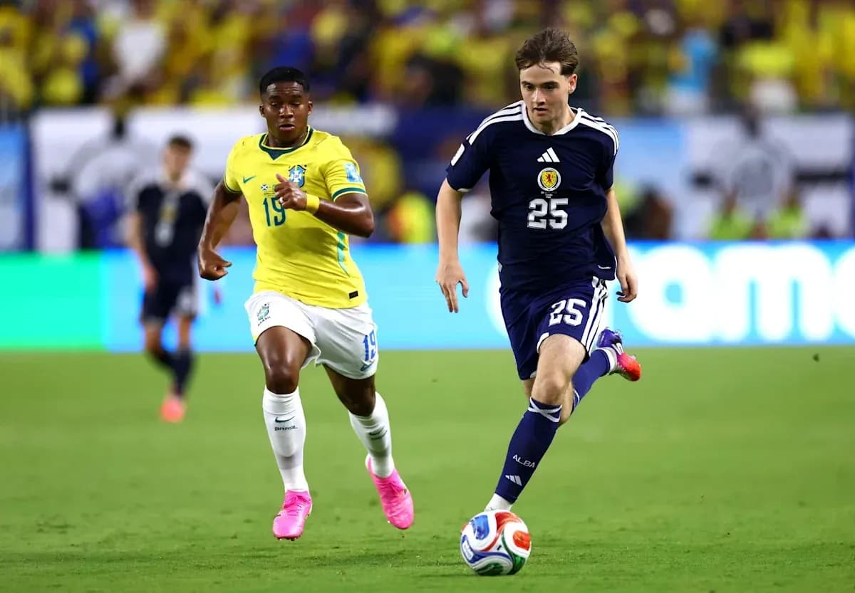 Jugador de Escocia corriendo con balón, seguido por jugador brasileño Jugador de Escocia corriendo con balón, seguido por jugador brasileño
