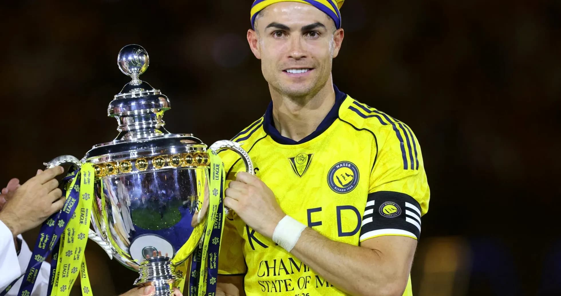 Jugador levantando trofeo con camiseta amarilla Jugador levantando trofeo con camiseta amarilla