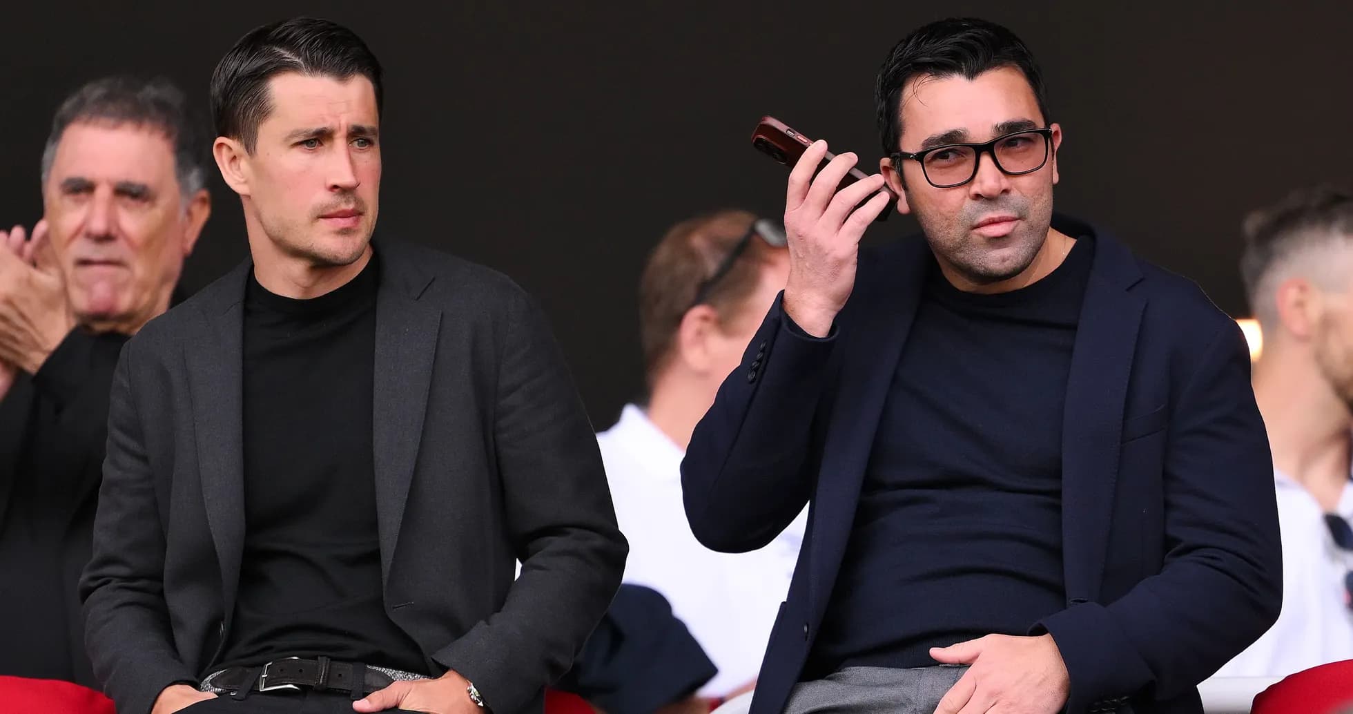 Dos hombres observando un evento deportivo desde las gradas Dos hombres observando un evento deportivo desde las gradas