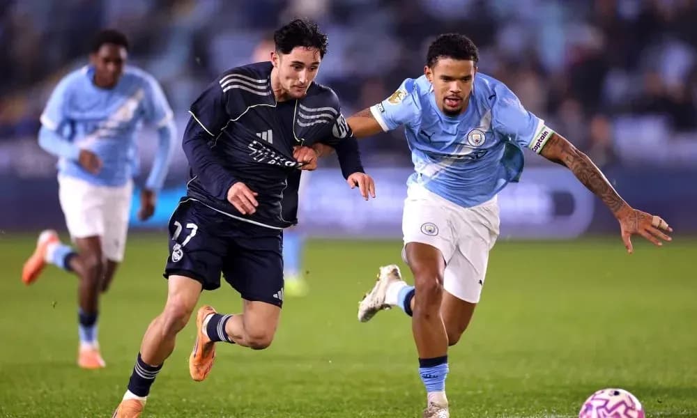 Jugador de Real Madrid corriendo con balón, seguido por jugador de Manchester City Jugador de Real Madrid corriendo con balón, seguido por jugador de Manchester City