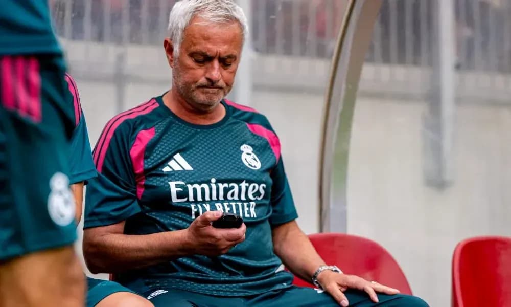 Entrenador sentado en el banquillo revisando su teléfono Entrenador sentado en el banquillo revisando su teléfono